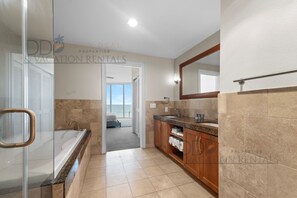 Une salle de bain moderne dotée d’une douche à parois de verre, d’une baignoire et d’un meuble-lavabo avec un évier et un plan de travail.