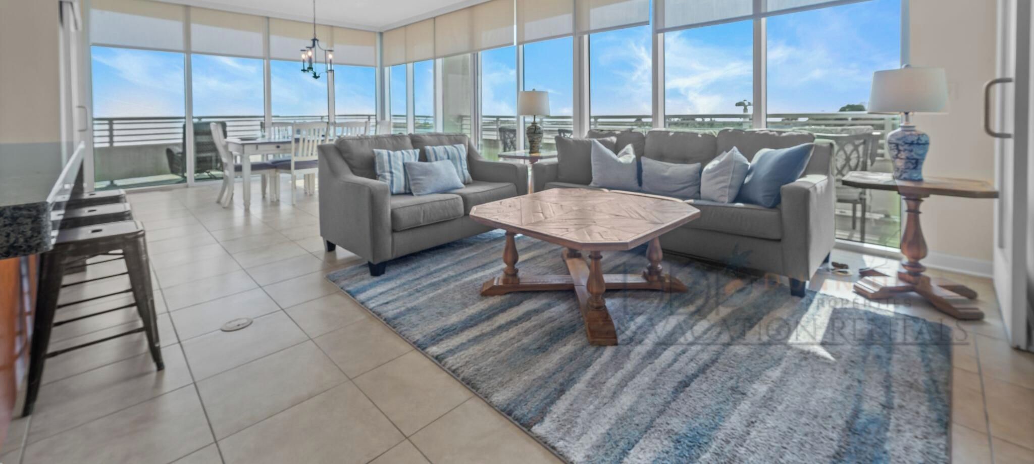 A spacious living room with a large window, a ceiling fan, and a dining area with a table and chairs.