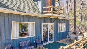 Une cabane avec une terrasse, deux fauteuils en osier, une table et une porte-fenêtre coulissante.