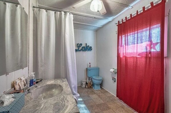 A bathroom with a marble bathtub, a toilet, and a shower curtain.