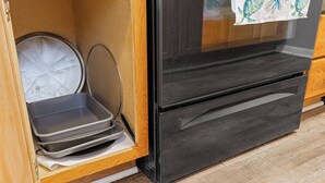 A kitchen with a black oven, a wooden cabinet, and a metal baking tray. - Spacious2BR/Work Crews & Families/Sleeps6/desk/Parking/WIFI/Pet friendly (Aurora)
