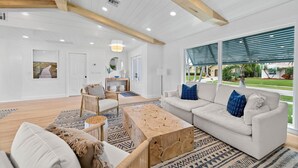 Un salón comedor amplio con techo alto, vigas de madera y grandes ventanales con vistas al exterior.
