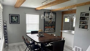 A dining area with a wooden table and chairs, a window with blinds, and a poster on the wall. - RARE CHANCE TO RENT THIS ND HOME 1.45 MILES FROM ND CAMPUS WITH IRISH PUB & MORE (South Bend)