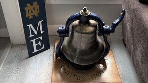 A room with a window, a welcome sign, and a bell on a wooden plaque. - RARE CHANCE TO RENT THIS ND HOME 1.45 MILES FROM ND CAMPUS WITH IRISH PUB & MORE (South Bend)
