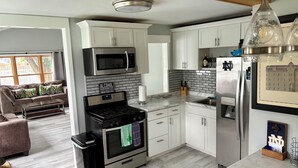 A modern kitchen with white cabinets, a stainless steel refrigerator, a microwave, and a stove. - RARE CHANCE TO RENT THIS ND HOME 1.45 MILES FROM ND CAMPUS WITH IRISH PUB & MORE (South Bend)