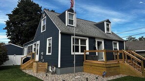 A two-story house with a dark blue exterior, white trim, and a wooden deck with a staircase. - RARE CHANCE TO RENT THIS ND HOME 1.45 MILES FROM ND CAMPUS WITH IRISH PUB & MORE (South Bend)