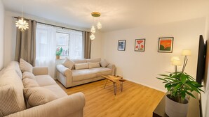 Un salon avec un canapé beige, une table basse en bois et une plante en pot.