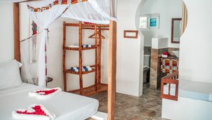 Un dormitorio con cama con dosel, una estantería de madera y vistas al baño.