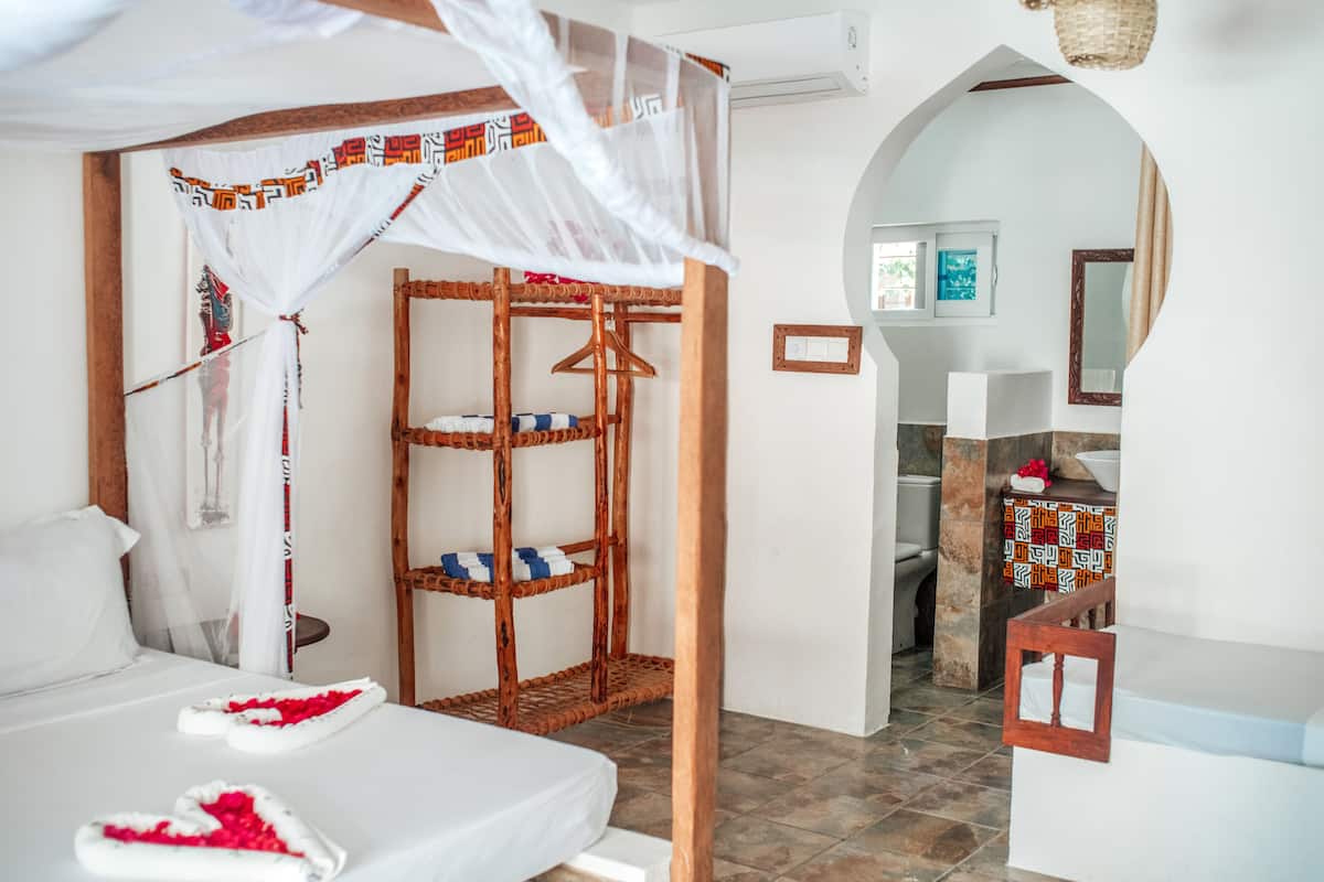 Un dormitorio con cama con dosel, una estantería de madera y vistas al baño.