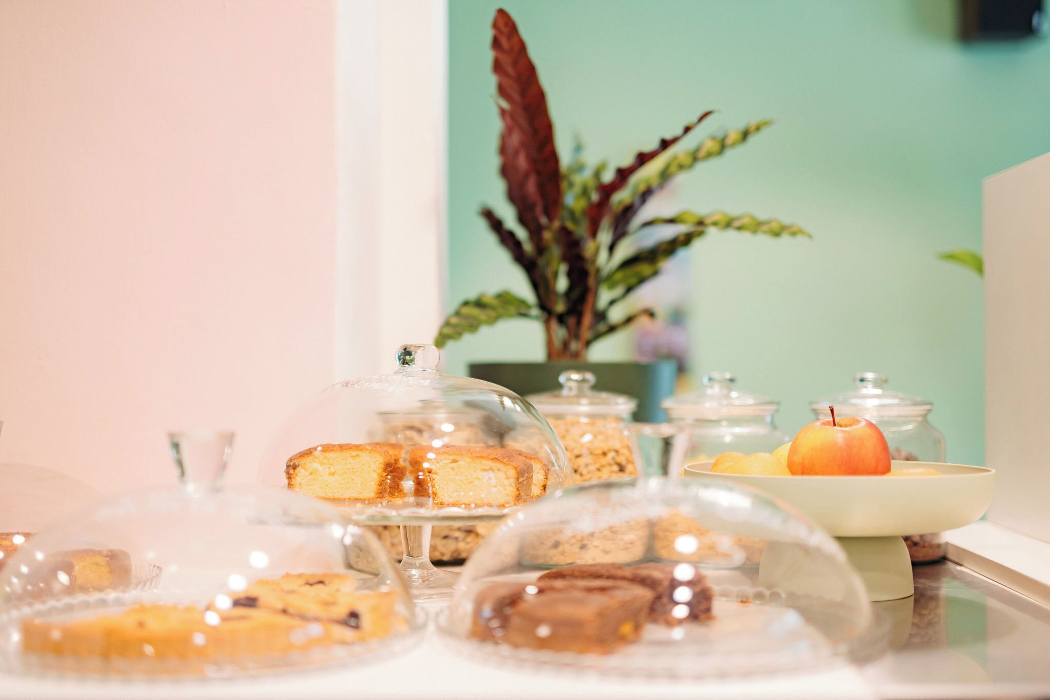 Una mesa de buffet con diversos postres bajo campanas de cristal.