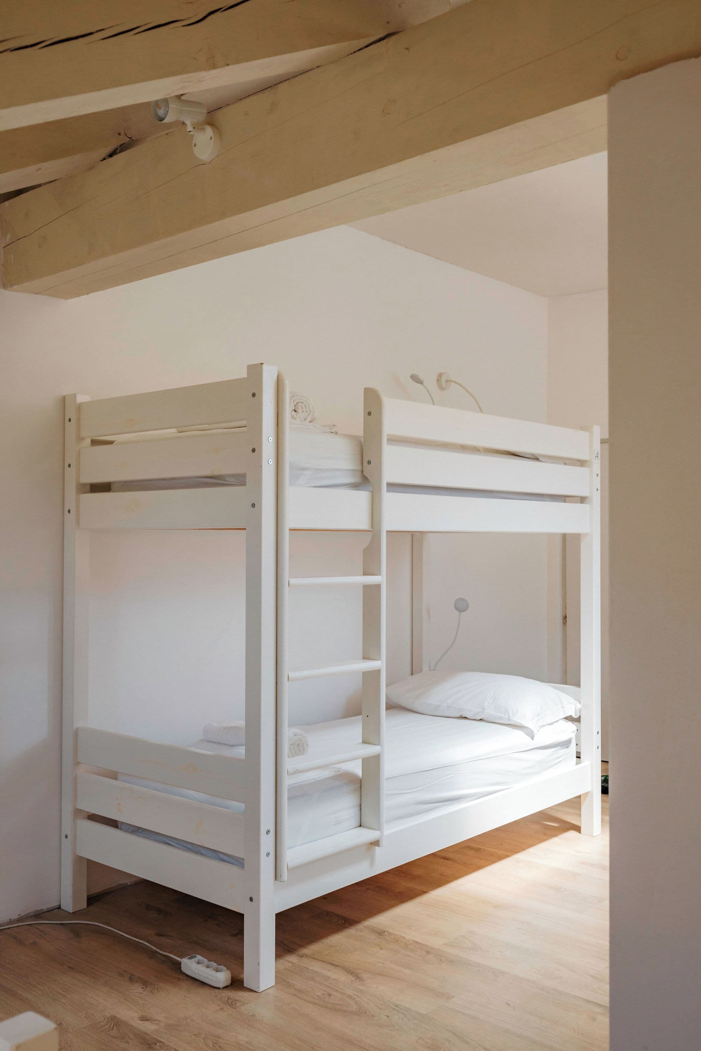 Una cama litera con escalera, un enchufe y un tomacorriente.