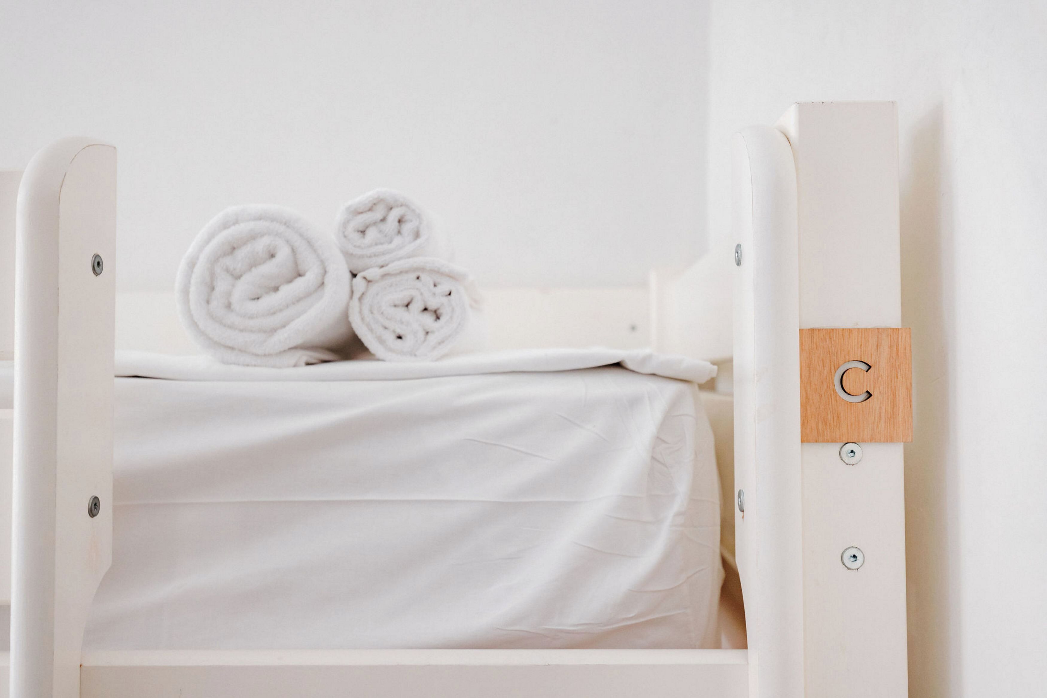 A white bunk bed with neatly rolled towels on the top bunk.