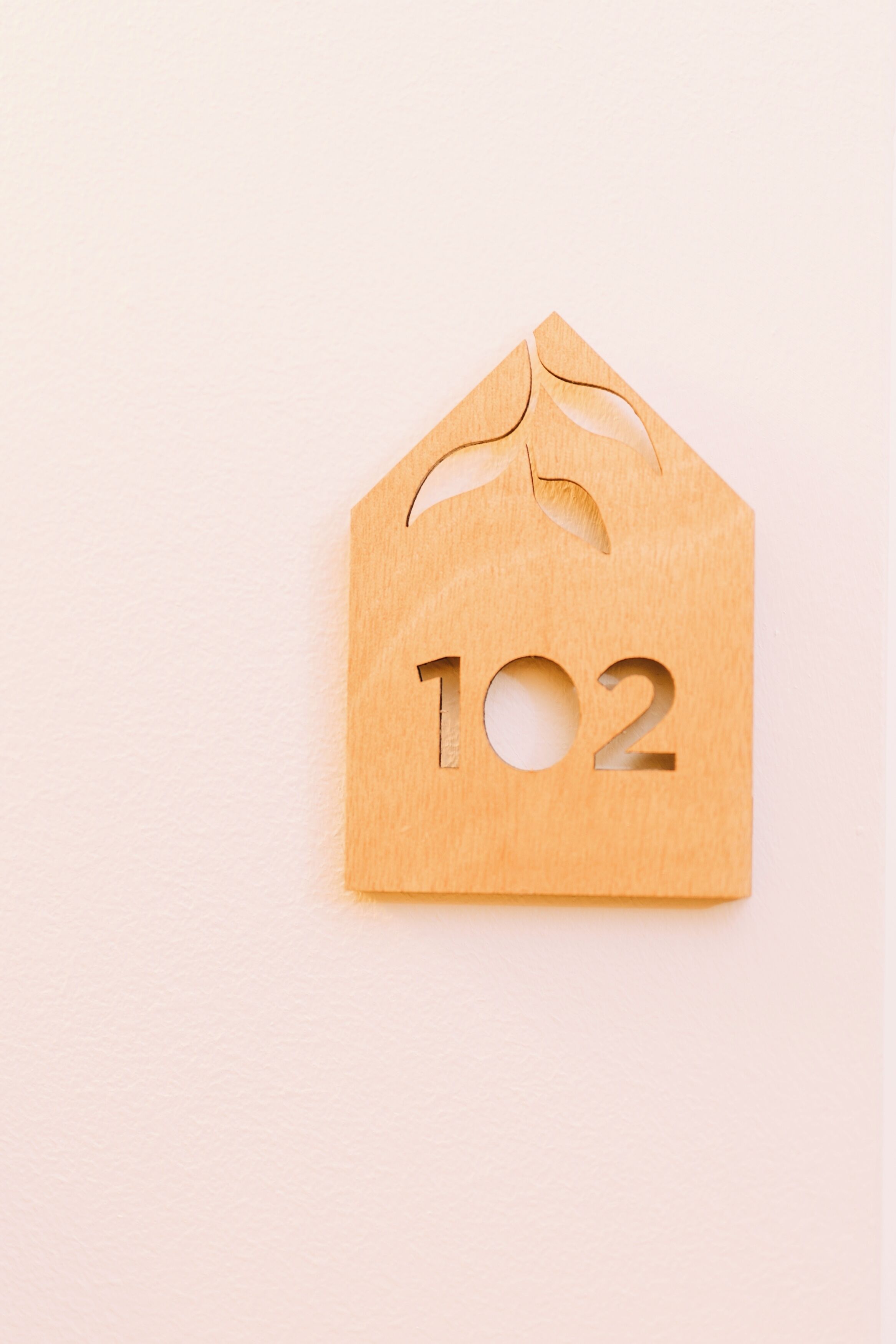 Un letrero con forma de casa de madera con el número 102 recortado.