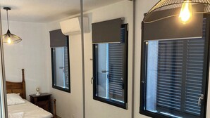 A bedroom with a large mirror, a bed, a bedside table, and a hanging light fixture. - New T3 apartment near the sea / port / large terrace / parking (Sanary-sur-Mer)