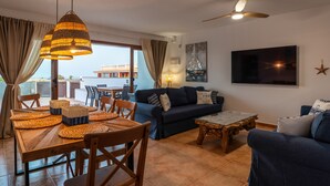A living room with a dining area, a ceiling fan, and a TV mounted on the wall. - Villa Skawi - Cliffside Retreat (Costa de Antigua)