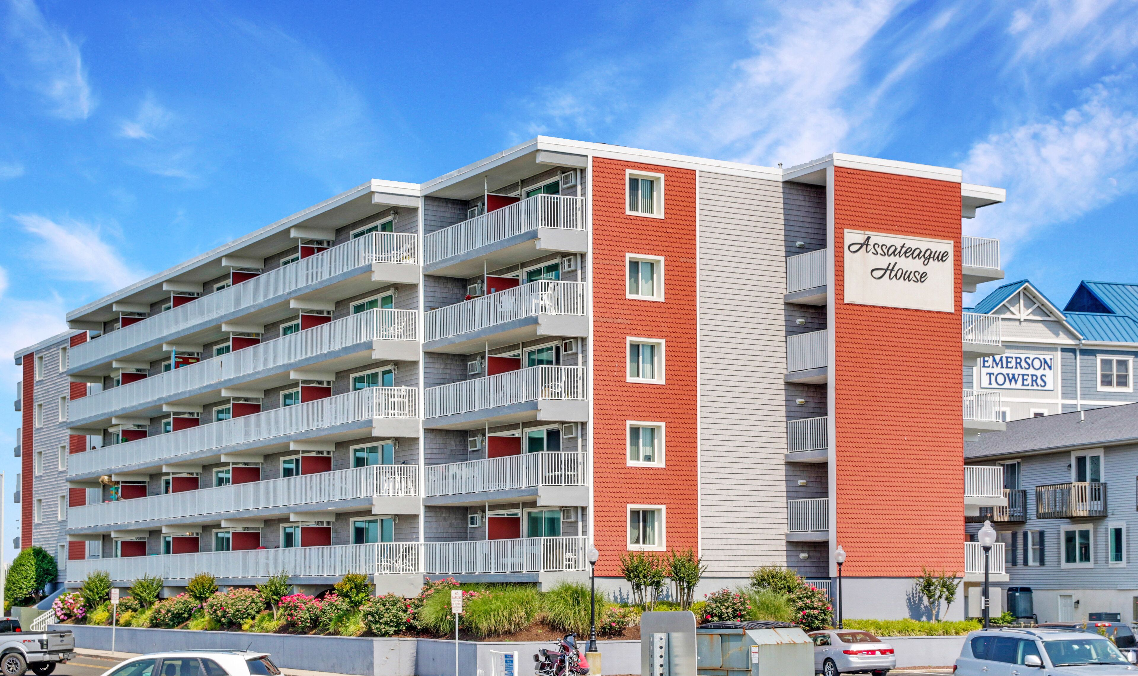 A multi-story hotel with balconies, a red and grey facade, and a sign indicating "Assateague House".