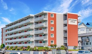 Un hotel de varios pisos con balcones, fachada roja y gris, y un cartel que dice 'Assateague House'.