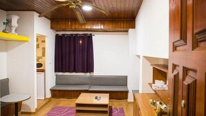 A cozy room with a wooden ceiling, a grey sofa, a small wooden table, and a purple curtain. - Hostel Benformoso (Lisbon)