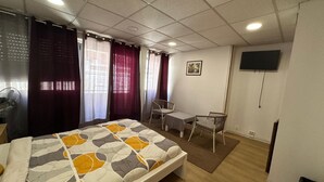 A bedroom with a bed, a desk, a chair, a TV, and a window with curtains. - Hostel Benformoso (Lisbon)