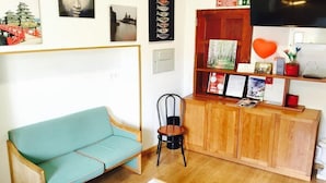 A reception area with a teal sofa, a wooden desk with a chair, and various framed items and decorations on the wall. - Hostel Benformoso (Lisbon)