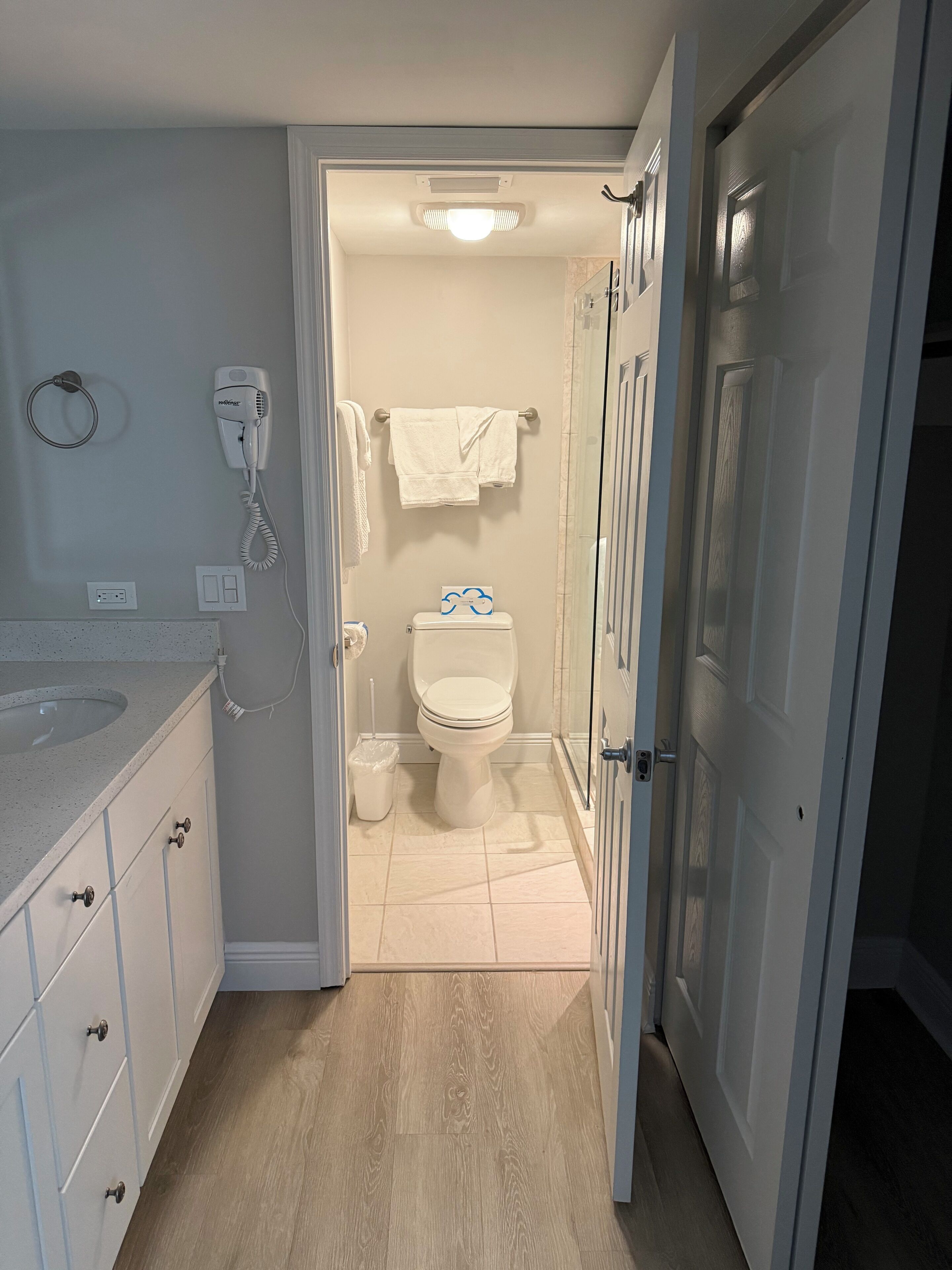 Un baño con inodoro, secamanos y toallero.
