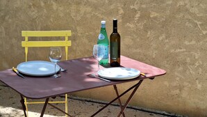 A table with plates, cutlery, a wine bottle, and a glass set against a textured wall.