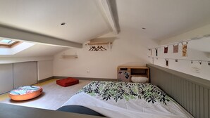 A compact room with a bed, a small seating area, a wardrobe, and a skylight.