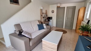 A living room with a sofa, a coffee table, a TV, and a plant.