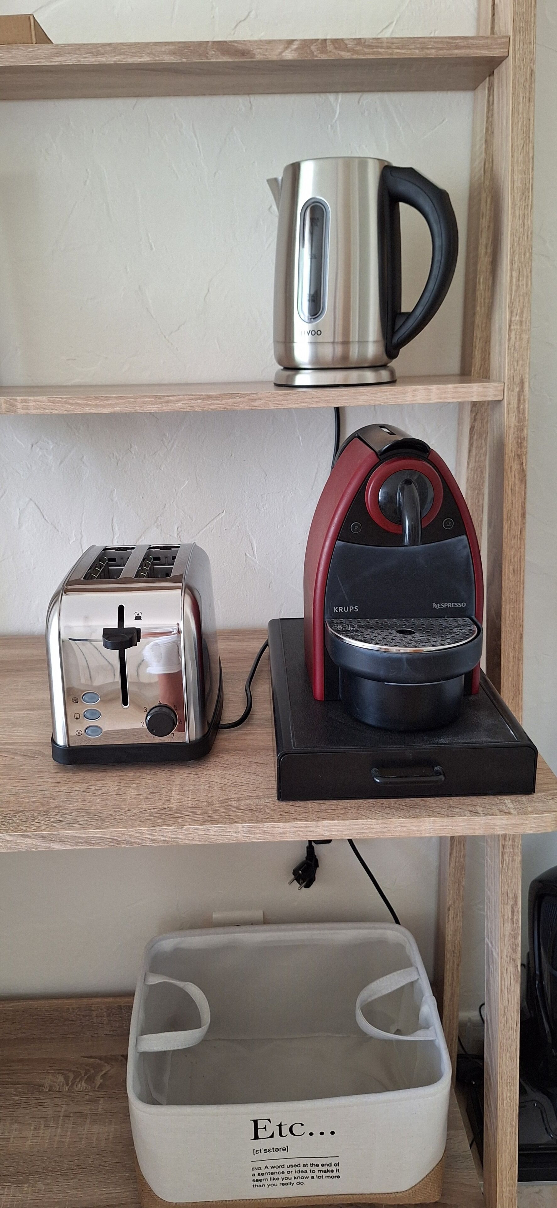 A kitchen shelf with a toaster, a Krups coffee maker, and a kettle.