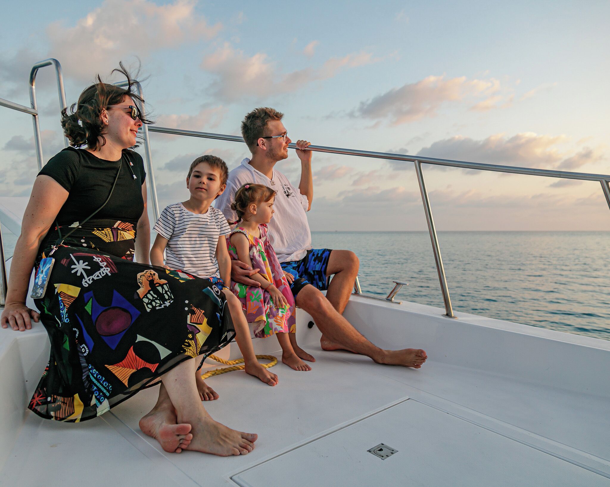 A family on a boat with a railing and a view of the sea.