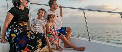 A family on a boat with a railing and a view of the sea.