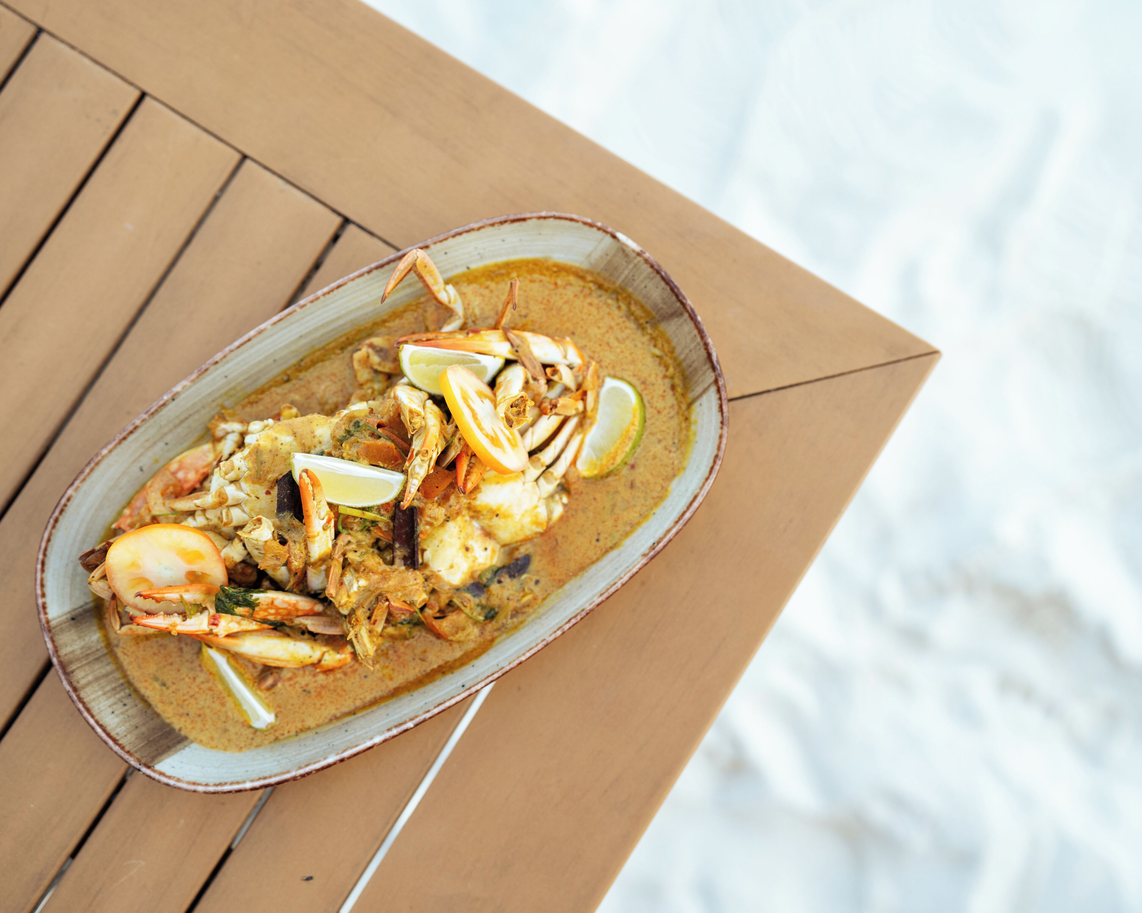 Un plat de fruits de mer servi dans un bol en céramique sur une table en bois.