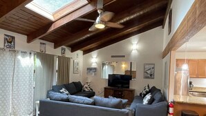 A living room with two sofas, a television, and a kitchen area with a refrigerator and stove.
