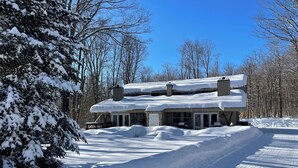 A two-story house with a snow-covered roof and a driveway leading to the entrance.