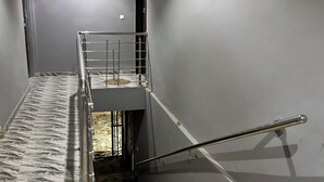 A staircase with a metal handrail, marble steps, and a grey wall. - Arek Condos- Your Charming Tropical Home Away from Home in the Heart of Accra. (Greater Accra Region)