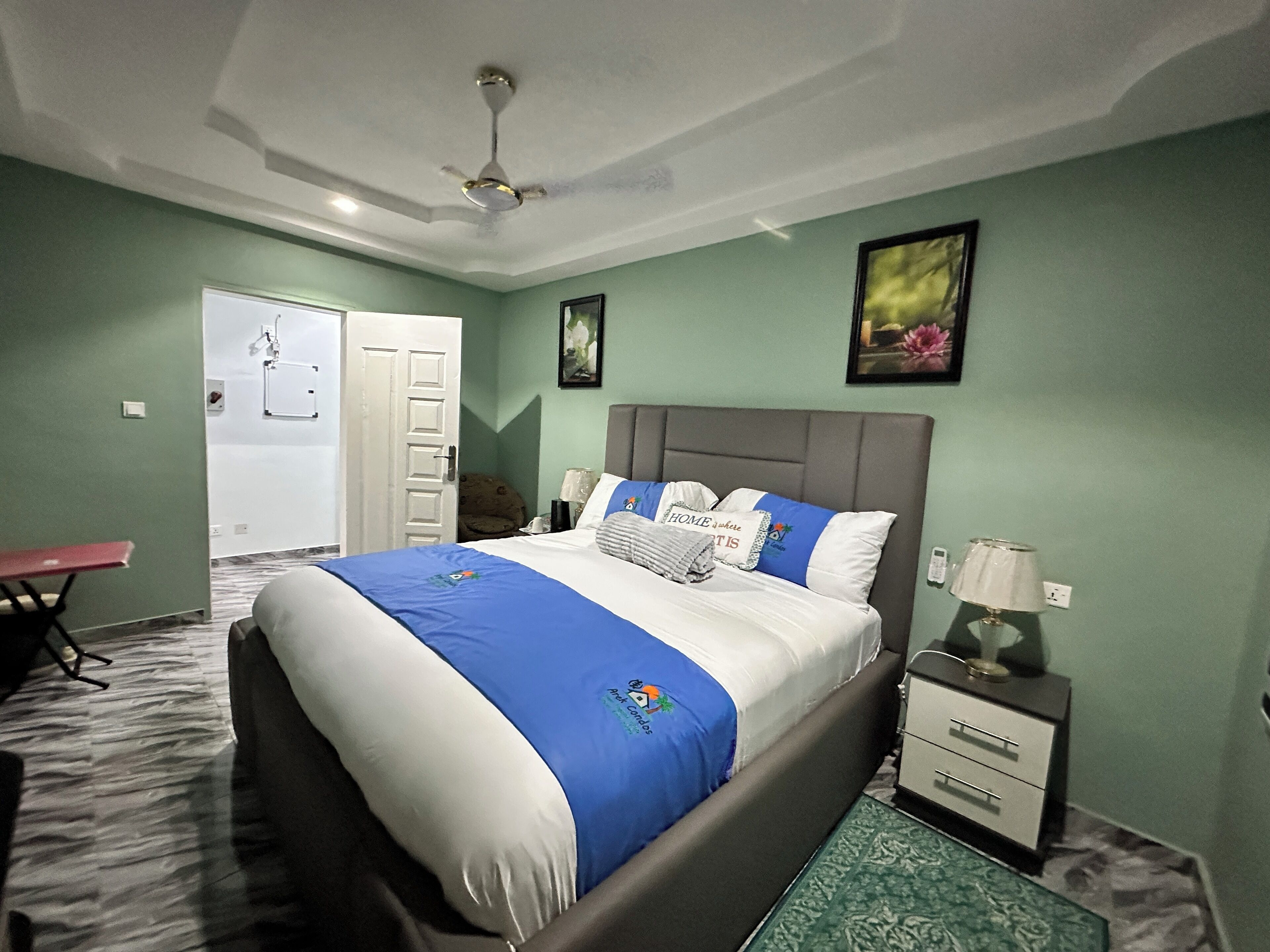 A bedroom with a bed, a nightstand, a desk, and a chair.