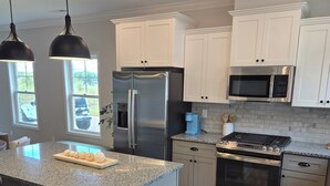A modern kitchen with a granite countertop, stainless steel appliances, and wooden flooring.
