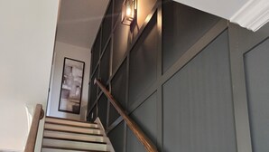 A staircase with wooden steps and a handrail, leading to a landing with a framed picture.