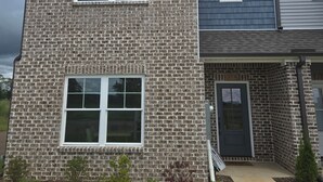 A two-story brick house with a front porch and a small front yard.