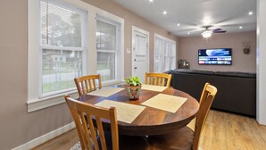 A dining area with a round wooden table, four wooden chairs, and a potted plant.