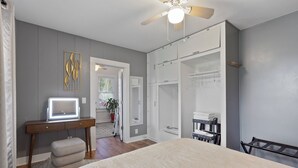 A bedroom with a bed, a desk with a computer, a wardrobe, and a ceiling fan.