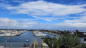 A marina with numerous boats docked along a narrow waterway, surrounded by a clear sky with scattered clouds.