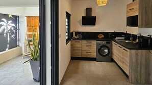 A modern kitchen with a built-in washer, wooden cabinets, and a pendant light.