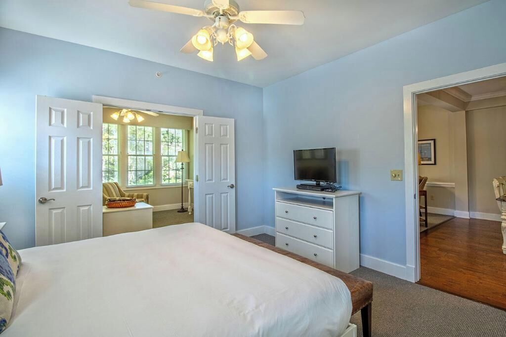 A bedroom with a bed, a TV on a dresser, and a ceiling fan.