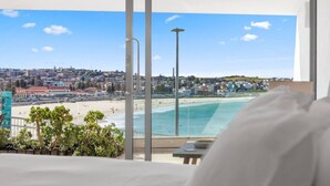 Ein Hotelzimmer mit großem Fenster mit Blick auf Strand und Stadtlandschaft.