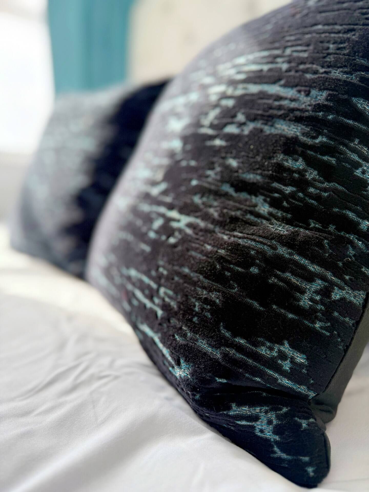 Primer plano de un almohadón con textura, tela oscura y diseños azul claro.
