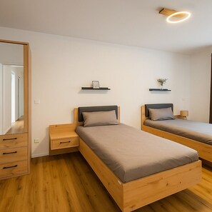 A bedroom with two single beds, wooden nightstands, a mirror, and a ceiling light fixture. - Stylish 3-room apartment in Leipzig | Central, modern, and perfect for 6 people (Leipzig)