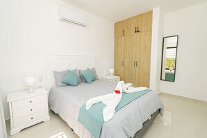 A bedroom with a bed, a nightstand, a wardrobe, and an air conditioning unit. - Tranquil 2BR Retreat in Bayahibe (San Rafael del Yuma)