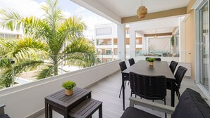 Un balcón con una mesa de comedor, sillas y una mesita con una planta.