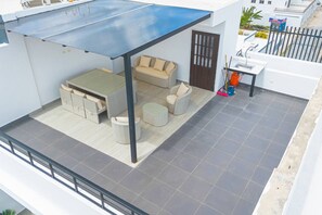 A rooftop patio with a covered seating area, a small table, and a sofa.